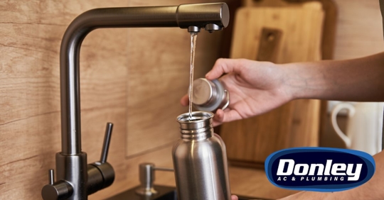 Person refilling water flask from tap