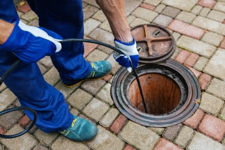 tech leading a hose down a sewer drain