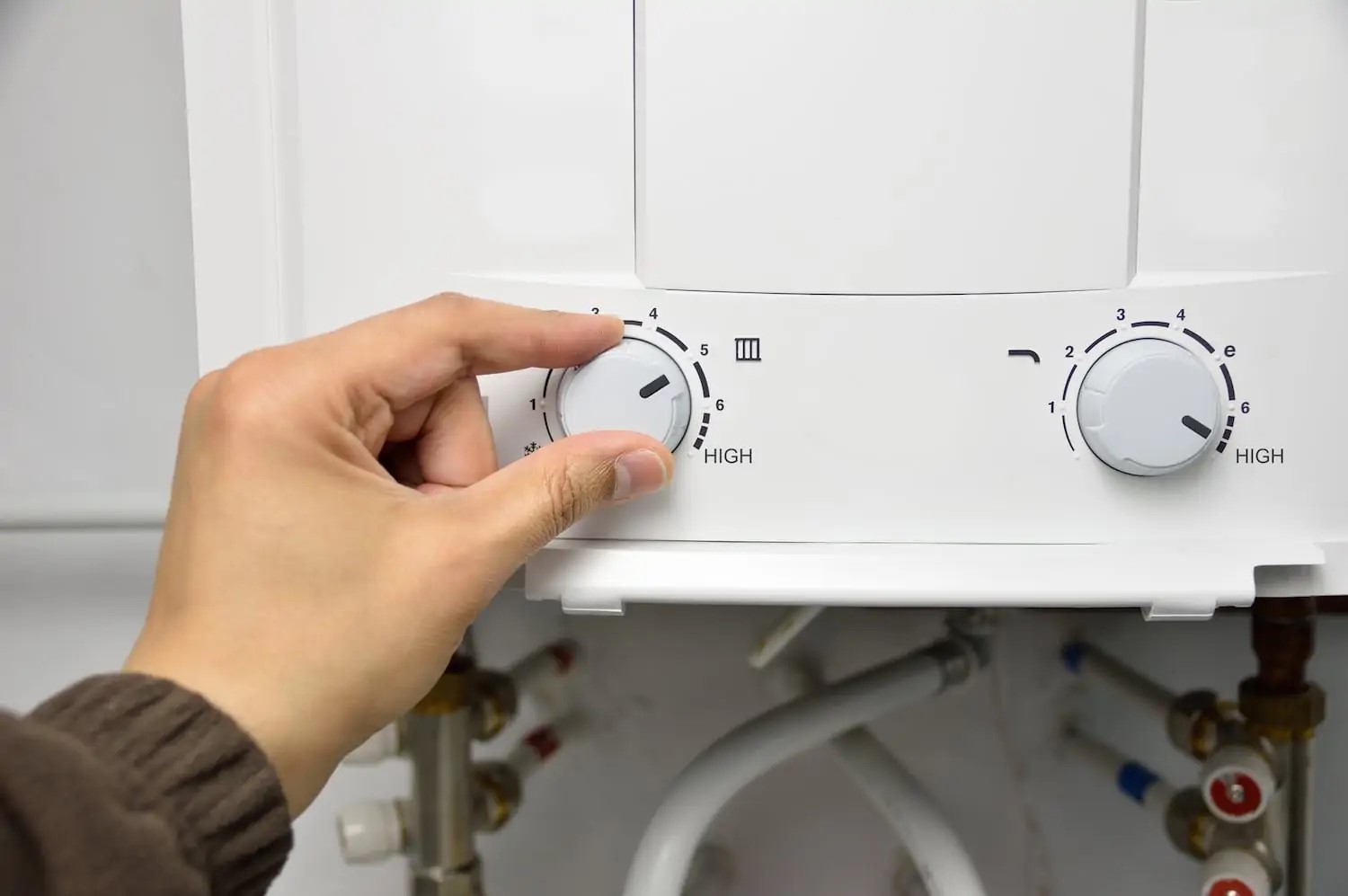 Hand adjusting settings on a water heater.