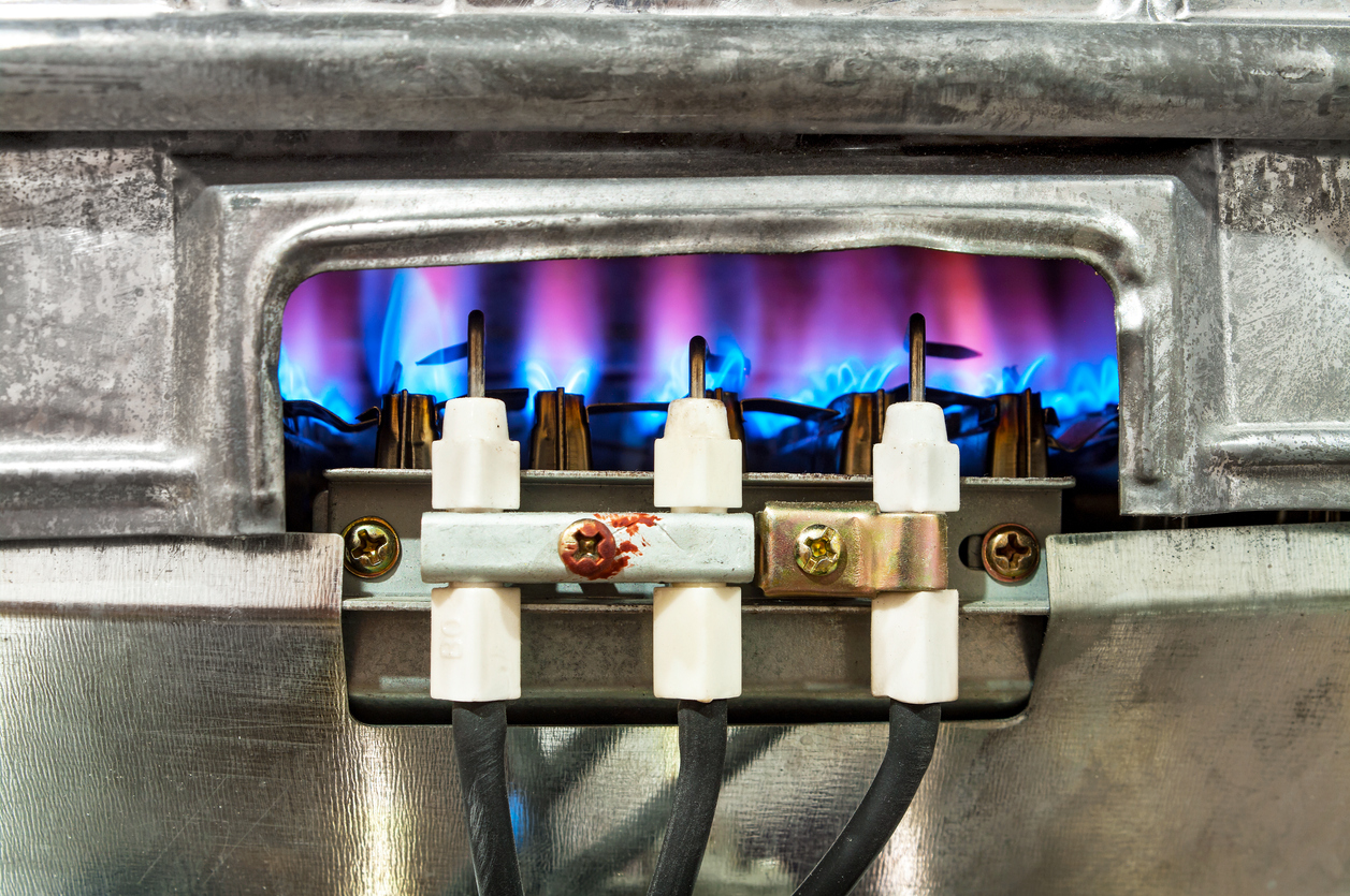 Pilot light lit, showing blue flames, on a gas water heater.