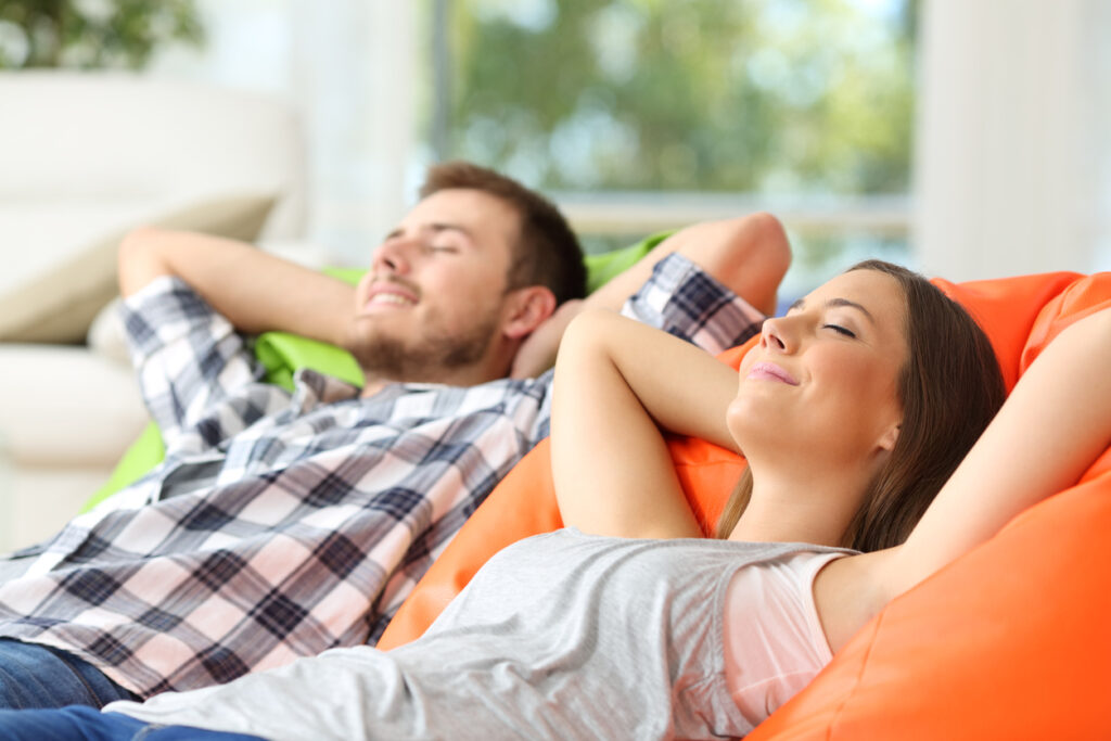 Couple or roommates relaxing lying on comfortable poufs in the living room at home, relaxing.